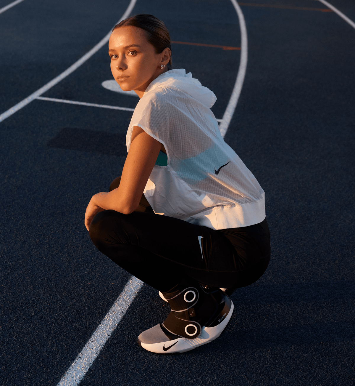 Vrouw zit gehurkt op een basketbalveld met de Hyperboot aan