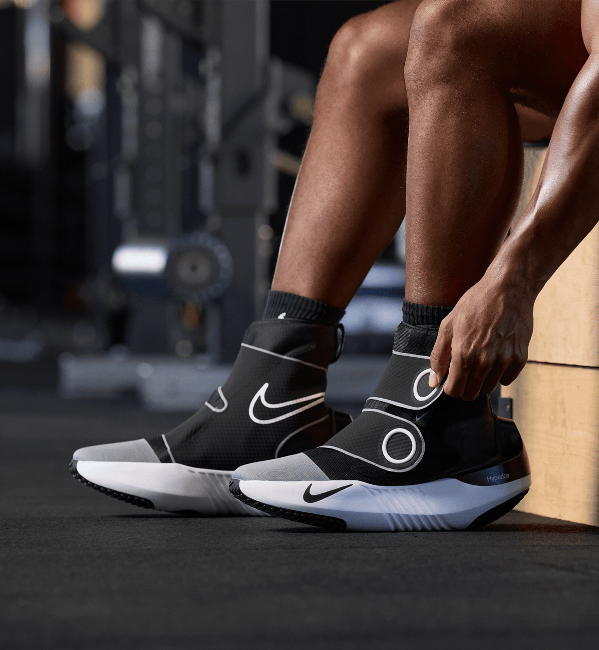 Person putting on the Hyperboot by Nike × Hyperice in a gym