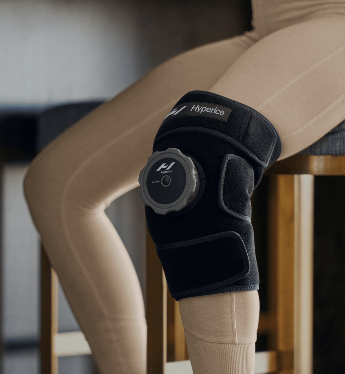 Persoon zit met de Hyperice Knee-ijscompressie om de knie