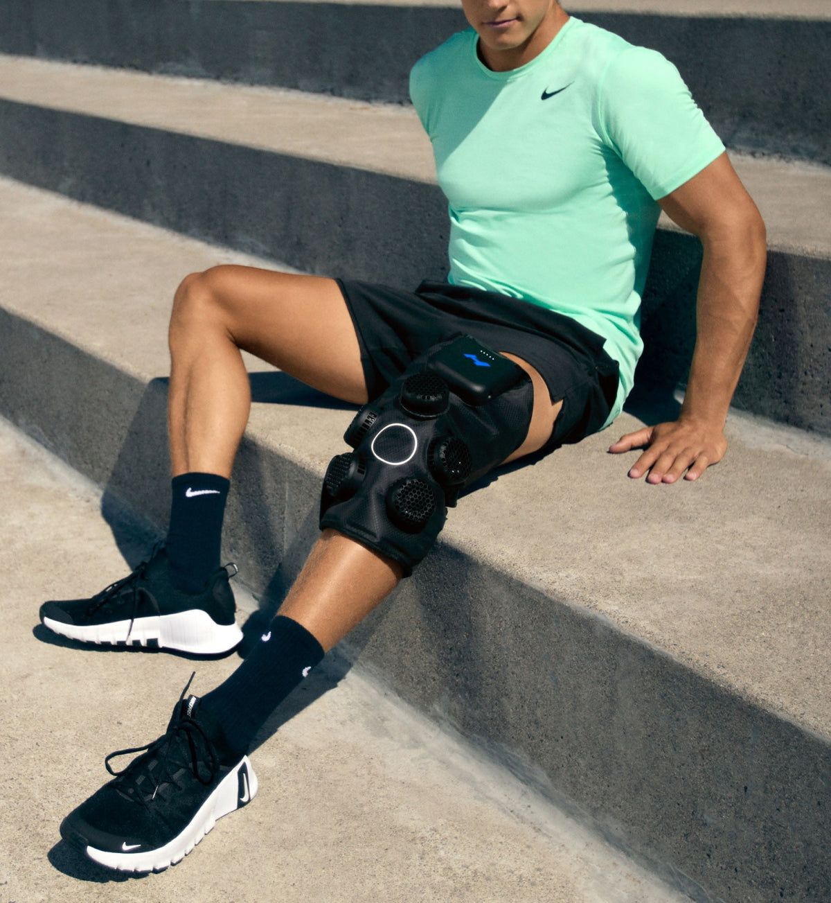 Person wearing a hyperice x 2 knee device sitting on concrete steps
